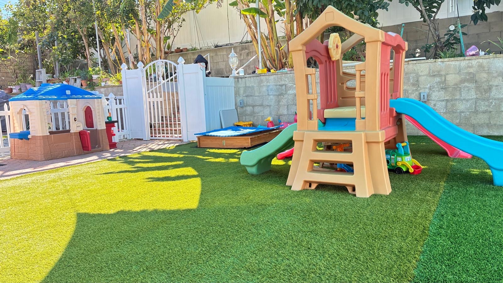 Outdoor play yard with slides and playhouses at Little Genius Home Daycare OC